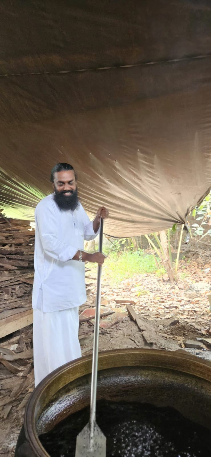 Vaidyar preparing medicine in a brass cauldron over wood-fire
